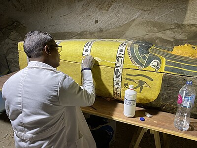 Restauration du sarcophage de dame Raou par Eweis Abdel Rady, à l’abri d’une des salles de l’immense tombe de Padiamenopé. ©Fr. Colin.Université de Strasbourg/Ifao 